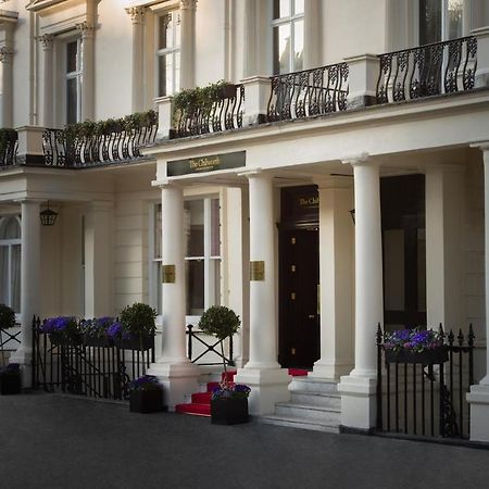 Montcalm Chilworth Townhouse, Paddington Hotel Londres Exterior foto The photo shows an elegant building entrance with classic architectural features. It has several tall, white columns supporting a balcony adorned with ornamental railings. The entrance is flanked by decorative planters with flowers. A set of steps le