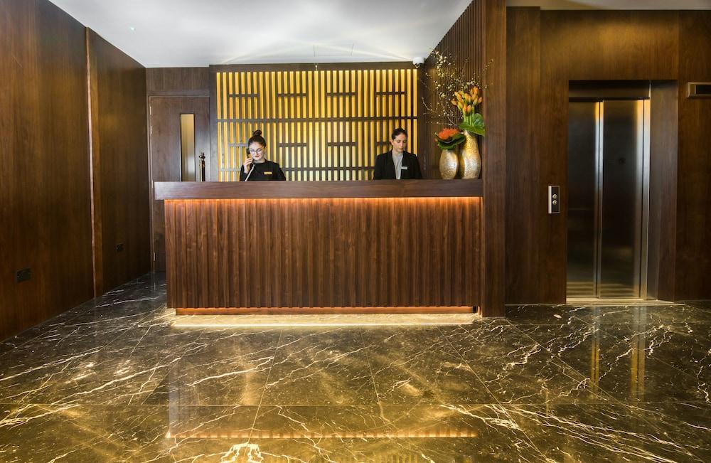 Montcalm Chilworth Townhouse, Paddington Hotel Londres Exterior foto The photo shows a hotel reception area. At the front desk, two employees are standing behind a wooden counter. The wall behind the counter features a modern design with lines, and there are decorative elements, including a vase with flowers. The floo