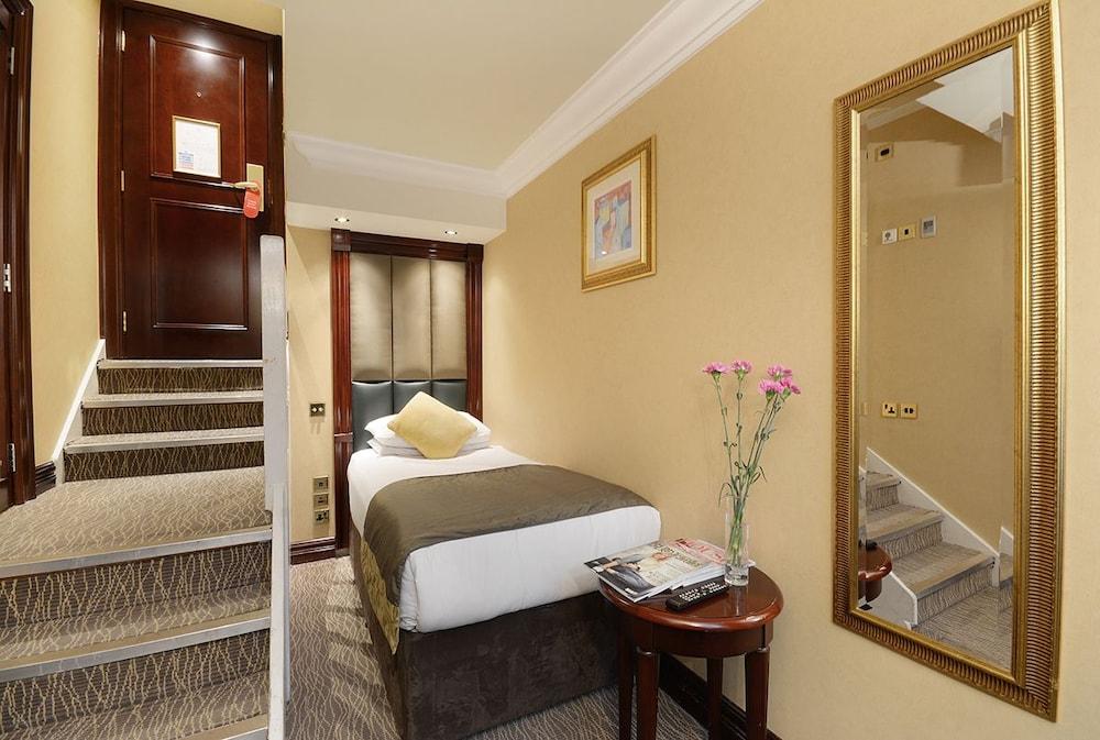 Montcalm Chilworth Townhouse, Paddington Hotel Londres Exterior foto The photo shows a small hotel room with a cozy atmosphere. On the left, there are stairs leading to another level, while the right side features a bed with a neutral-colored bedspread. A small table beside the bed holds some magazines and a vase with