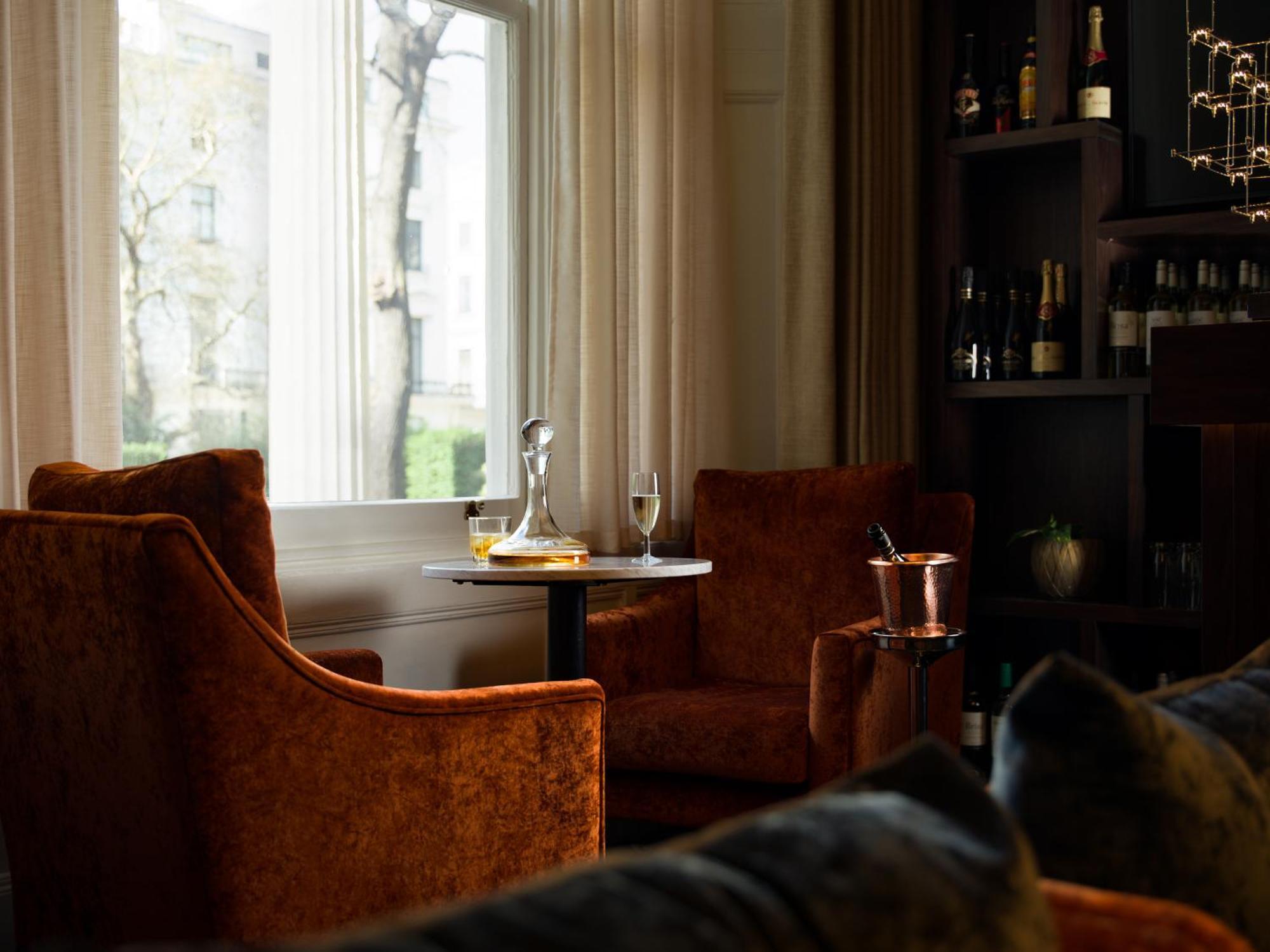 Montcalm Chilworth Townhouse, Paddington Hotel Londres Exterior foto The photo depicts a cozy interior setting featuring two orange velvet armchairs positioned around a small round table. On the table, there’s a glass decanter and a flute glass, suggesting a setting for drinks. A silver ice bucket is also present. In 