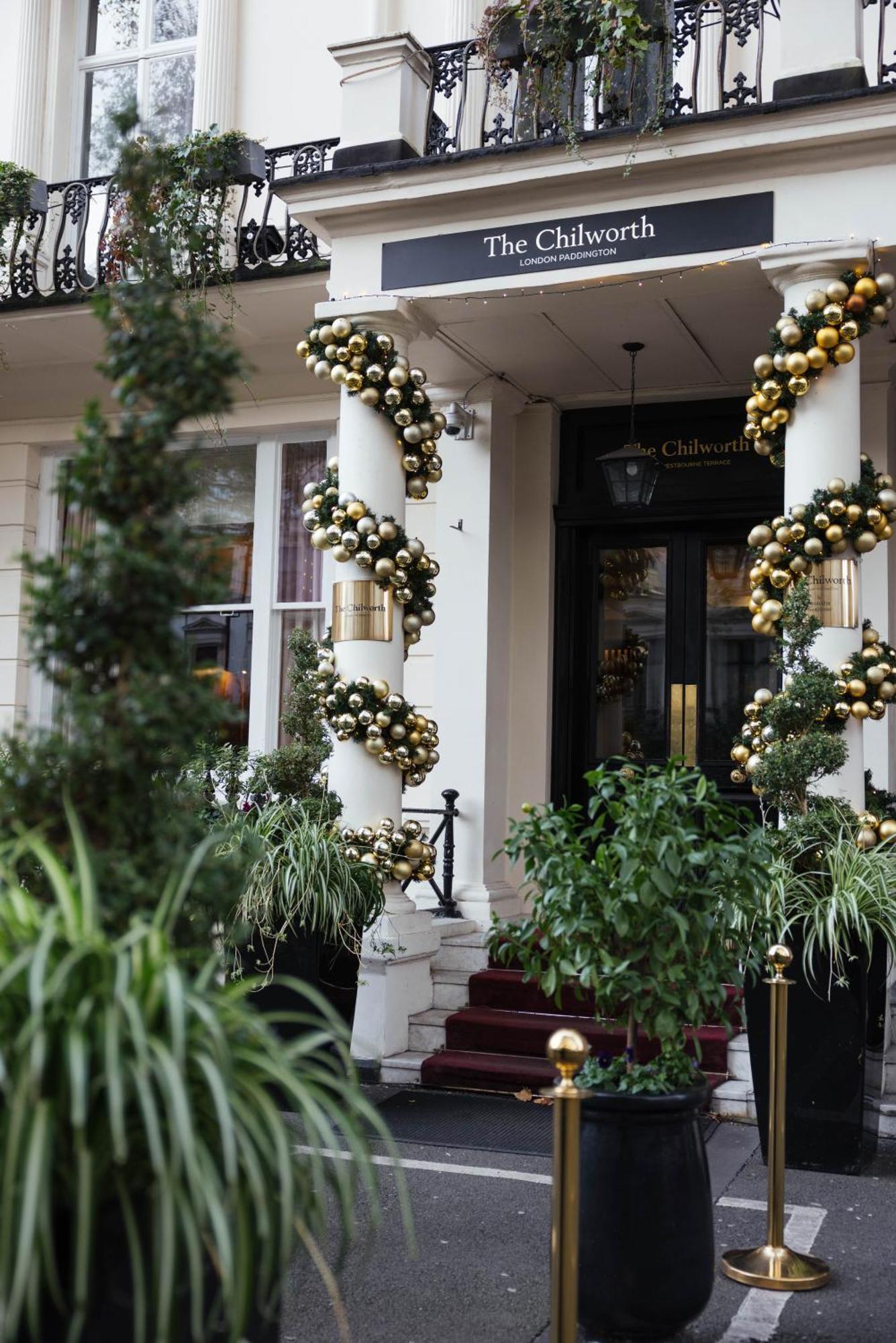 Montcalm Chilworth Townhouse, Paddington Hotel Londres Exterior foto The photo shows an elegant entrance to a building, decorated with festive adornments. There are two tall columns wrapped in garlands made up of gold and black ornaments, giving a luxurious appearance. On either side of the entrance, there are potted 