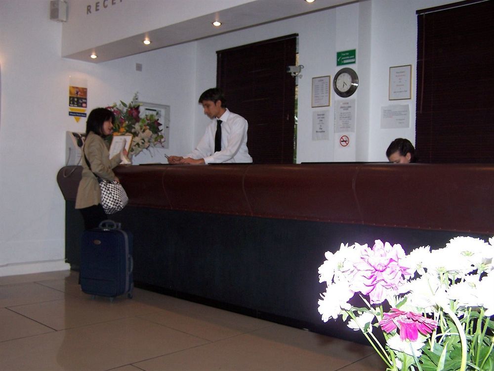 Montcalm Chilworth Townhouse, Paddington Londres Exterior foto The photo shows a hotel reception area. There is a front desk behind which a staff member in a white shirt is attending to a guest. The guest, who is holding a bag and has a suitcase beside them, appears to be checking in. The reception area is decor