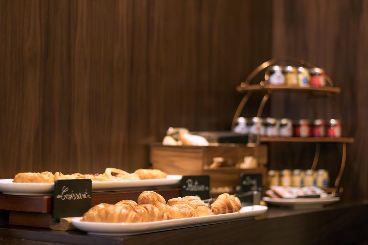 Montcalm Chilworth Townhouse, Paddington Hotel Londres Exterior foto The photo shows a display of various baked goods and condiments. On the left, there are several trays of pastries, including croissants, placed on a wooden surface. Each pastry is labeled with a small sign, potentially indicating their names or types