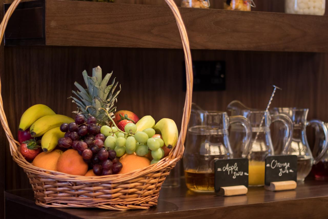 Montcalm Chilworth Townhouse, Paddington Hotel Londres Exterior foto The photo shows a wicker basket filled with a variety of fruits, including bananas, oranges, grapes, and a pineapple. In the background, there are several glass pitchers and chalkboard signs that indicate "apple juice" and "orange juice." The setting